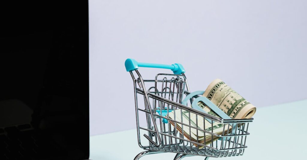 Mini shopping cart with rolled cash next to a laptop, representing online shopping.